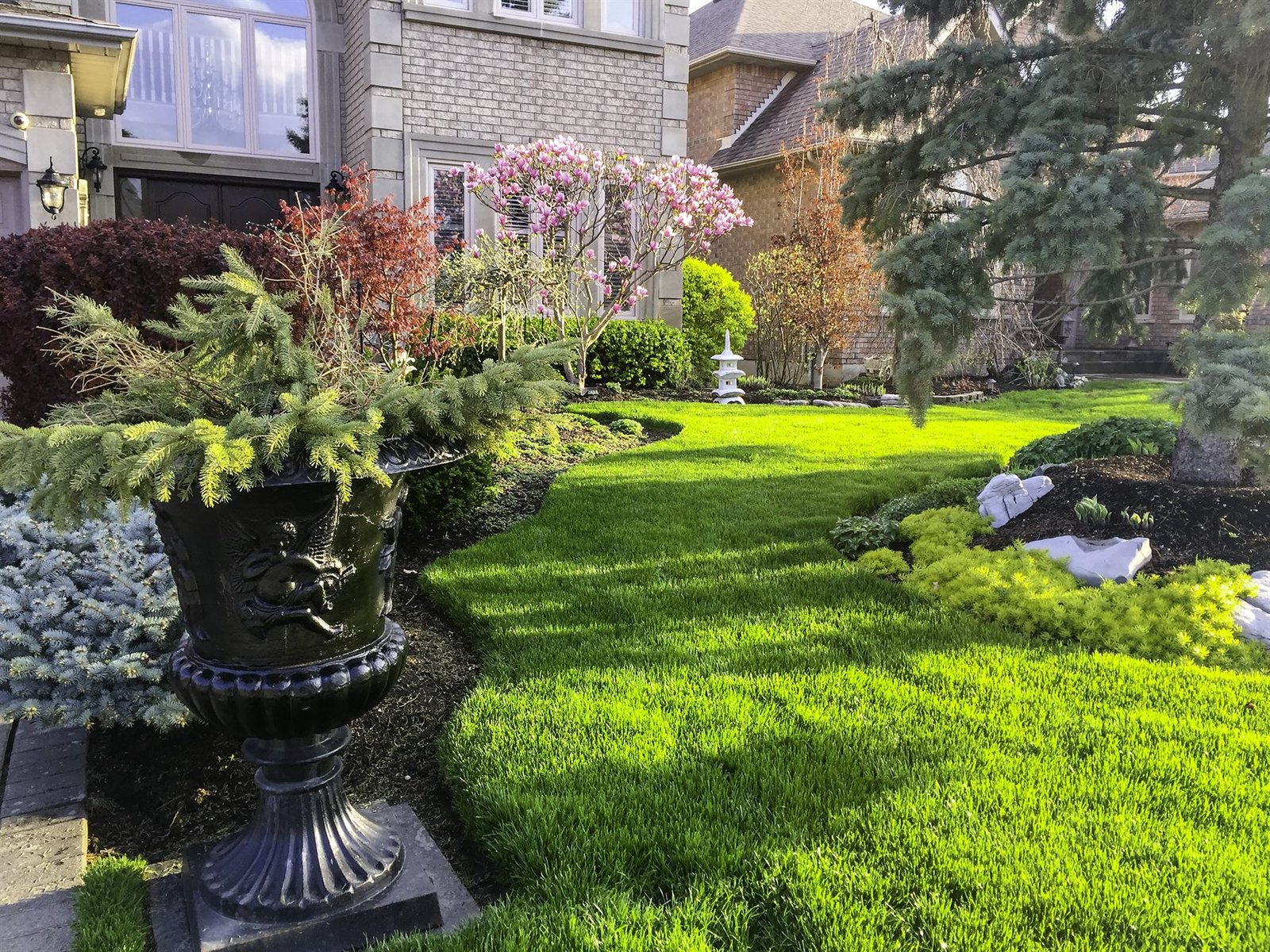 Jardín residencial premium con césped y canteros cuidados